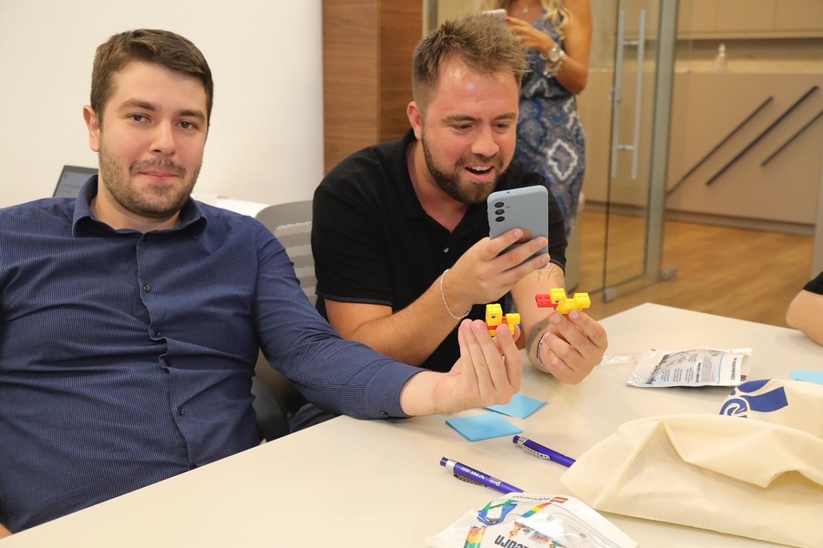 two men are admiring their LEGO duck builds during facilitator training session